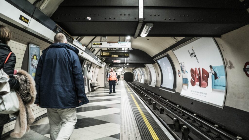 man in blue jacket standing on train station